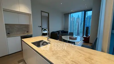 Modern open-plan kitchen and living room with city skyline view, featuring sleek countertops and stylish decor.