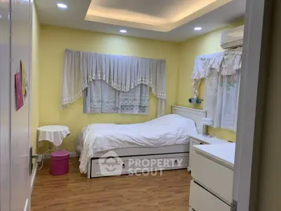 Cozy bedroom with wooden flooring and elegant white furnishings.