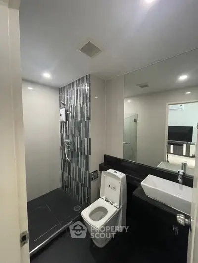 Modern bathroom with sleek design, featuring a glass shower and contemporary fixtures.