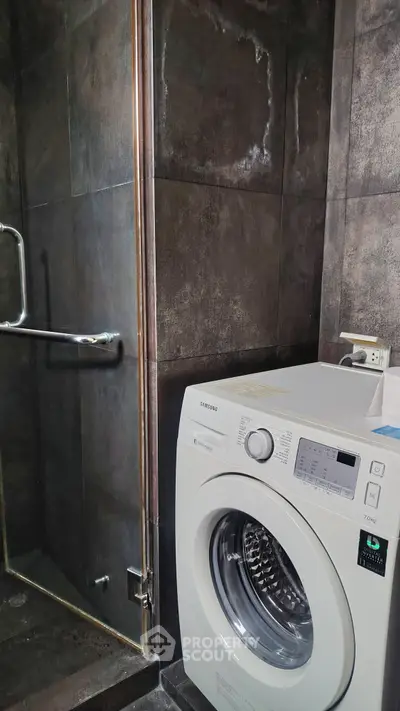 Modern bathroom with washing machine and sleek dark tiles