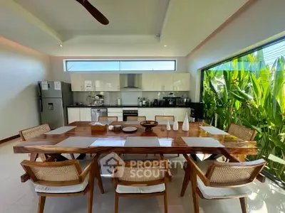 Spacious modern kitchen with large wooden dining table and lush garden view, perfect for entertaining.