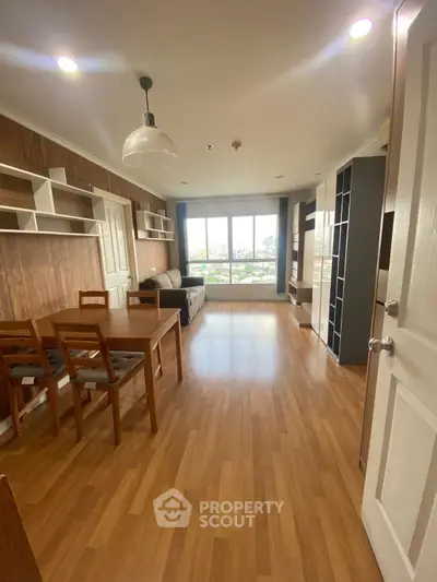 Spacious living room with wooden flooring and large window view.
