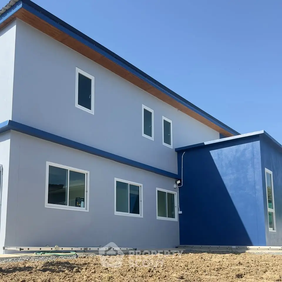 Modern two-story blue and white house with large windows and minimalist design.