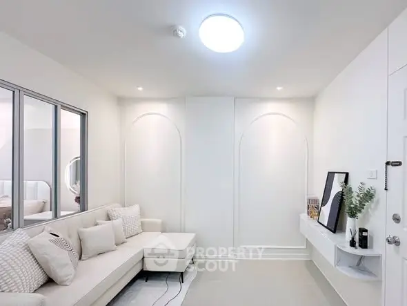 Modern minimalist living room with white decor and cozy sectional sofa.