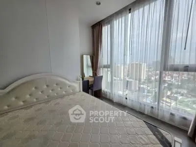 Spacious bedroom with large windows offering stunning city views, perfect for urban living.