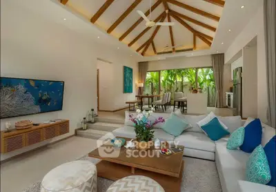 Luxurious living room with vaulted ceiling and tropical decor, featuring a spacious seating area and garden view.