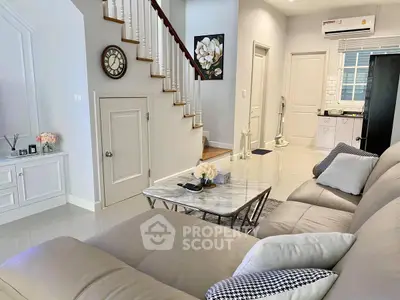 Spacious living room with elegant staircase and modern decor in a stylish home.