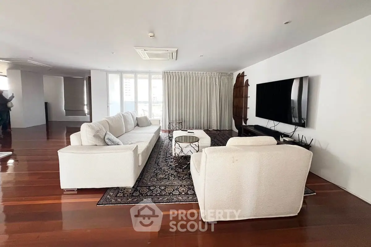 Spacious modern living room with elegant white furniture and large TV, perfect for relaxation.