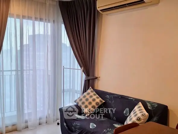 Cozy living room with stylish sofa and air conditioning, featuring elegant curtains and a bright ambiance.