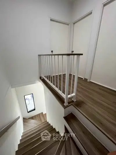 Modern staircase with wooden flooring and white railing in a contemporary home interior.