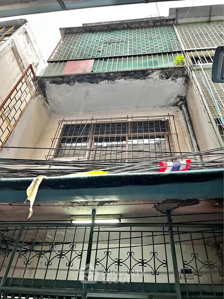 Charming urban building facade with secure metal grilles and vintage architectural details.