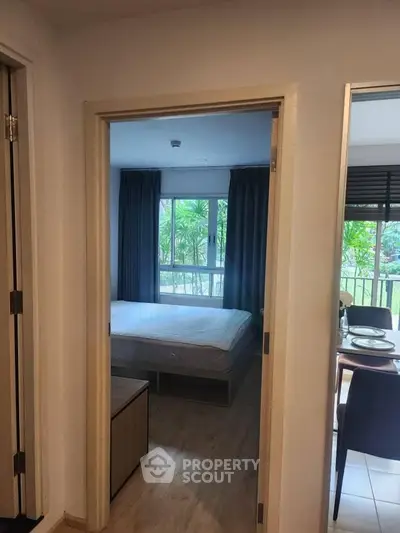 Cozy bedroom with large window and garden view, adjacent to dining area in modern apartment.
