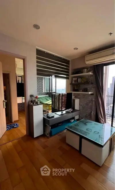 Modern living room with wooden flooring, large window, and stylish furniture in a high-rise apartment.