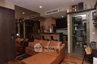 Modern living room with leather sofa and open kitchen layout, featuring stylish decor and wooden flooring.