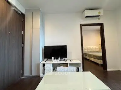 Modern living room with TV and air conditioning, leading to a cozy bedroom.