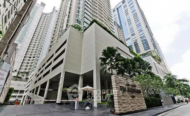 Modern high-rise building with lush greenery and elegant entrance in urban setting.