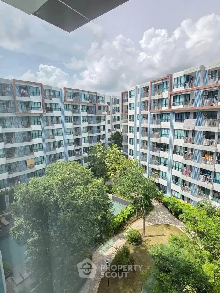 Modern apartment complex with lush garden and pool view, perfect for urban living.