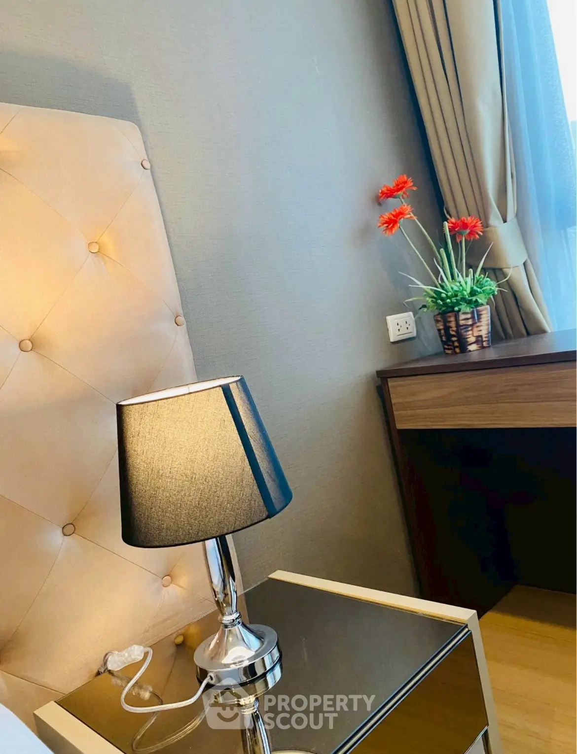 Elegant bedroom corner with stylish lamp and floral decor, perfect for modern living.