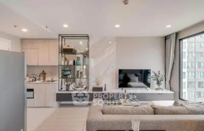 Modern living room with open kitchen, stylish decor, and large window view in urban apartment.