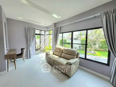 Bright living room with large windows and garden view, featuring a comfortable sofa and modern decor.