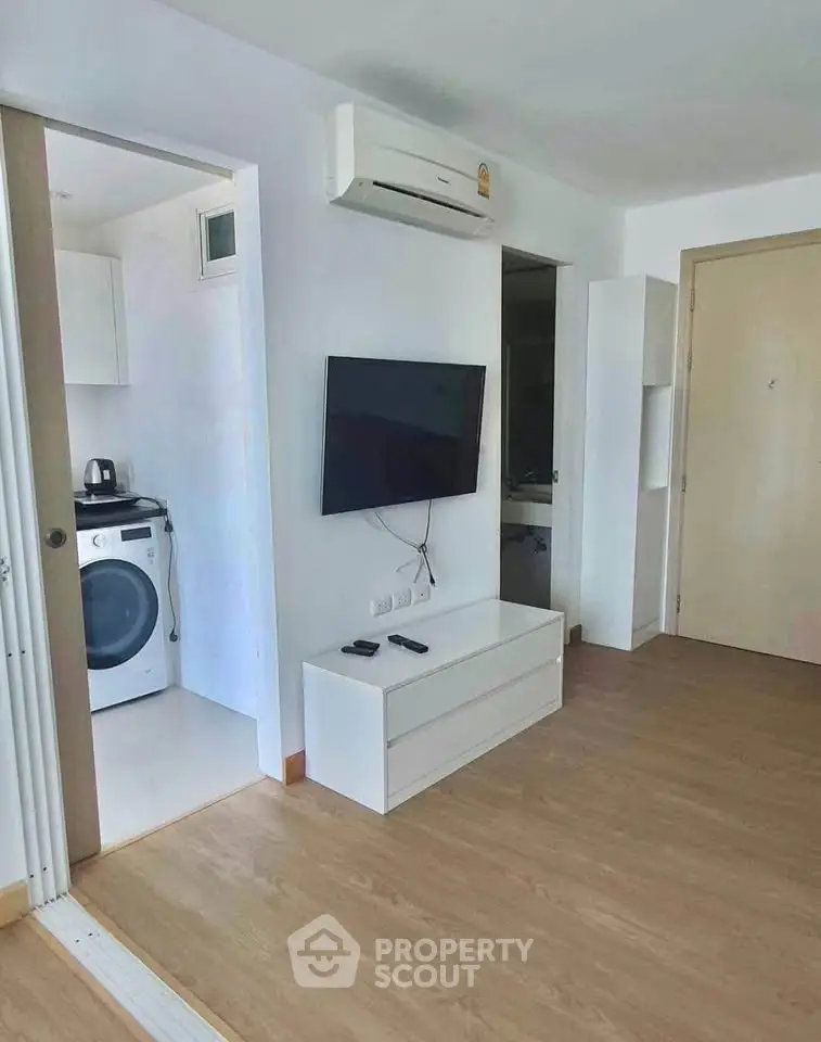 Modern apartment interior with air conditioning, wall-mounted TV, and in-unit washing machine.