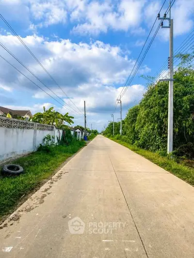 Scenic suburban road with lush greenery and clear blue sky, ideal for peaceful living.