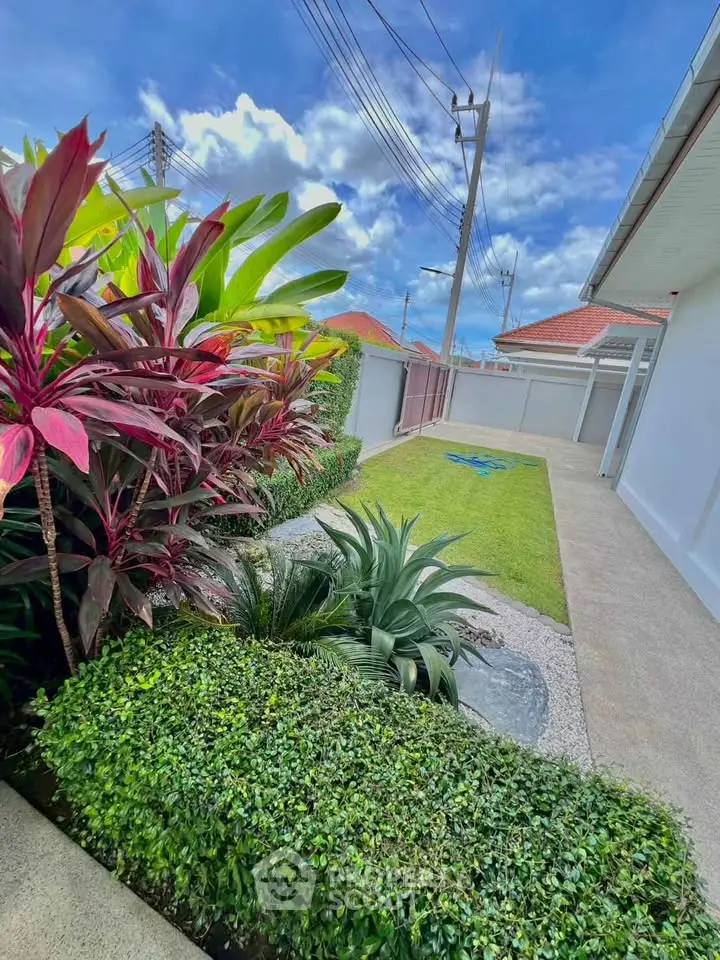 Beautiful garden with lush greenery and clear blue sky in a modern residential area.