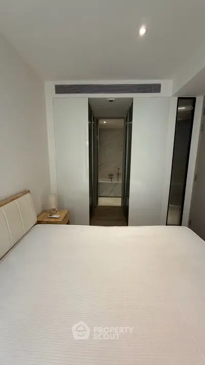 Modern bedroom with ensuite bathroom featuring sleek design and neutral tones.
