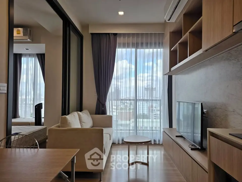 Modern living room with large windows and natural light in a stylish apartment.