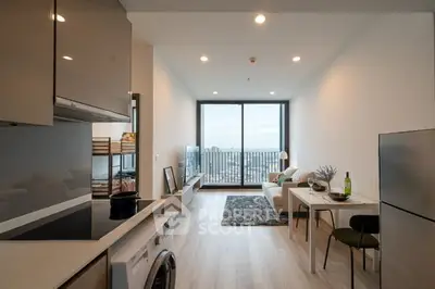 Modern living room with open kitchen and city view balcony.