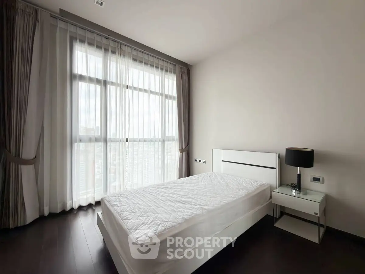 Modern bedroom with large window and minimalist decor in high-rise apartment