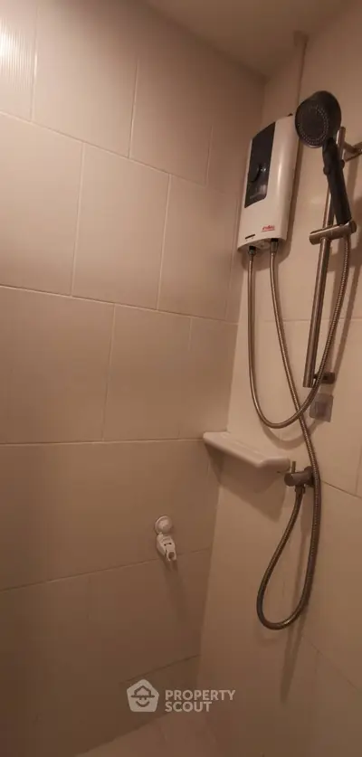 Compact bathroom shower area with water heater and tiled walls.