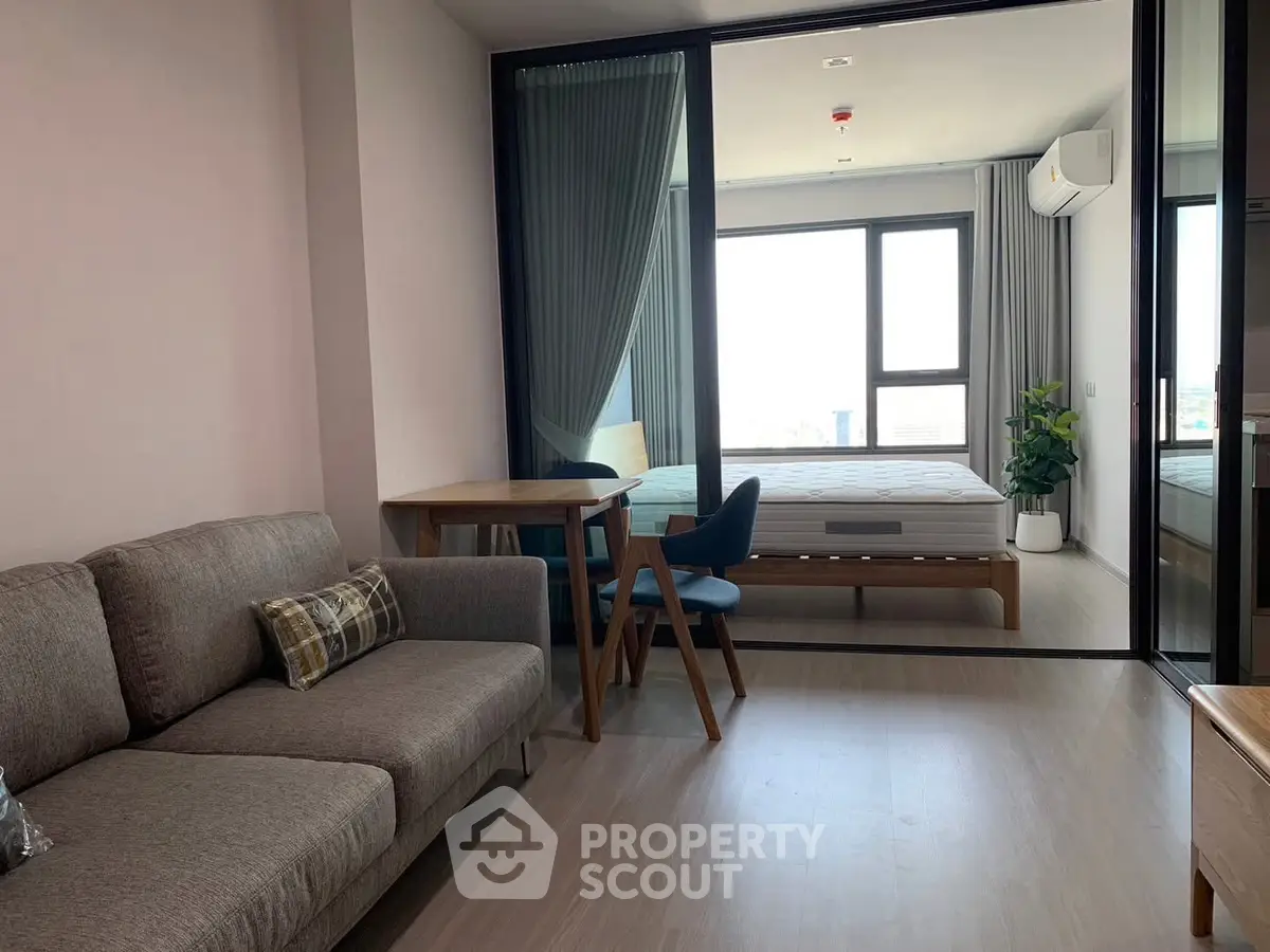 Modern apartment with open living room and bedroom, featuring stylish furniture and large windows.