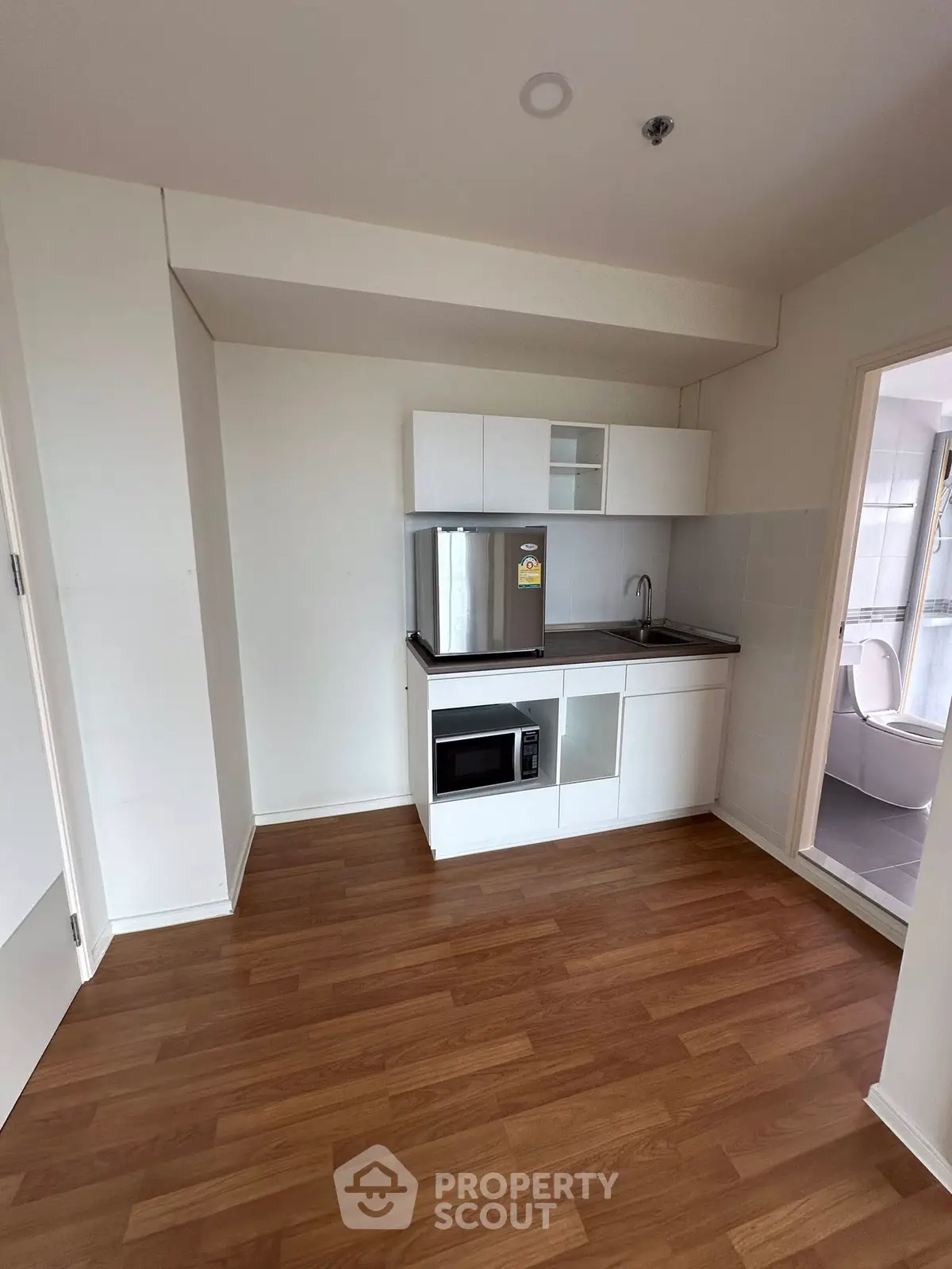 Compact kitchen with modern appliances and wooden flooring in a cozy apartment