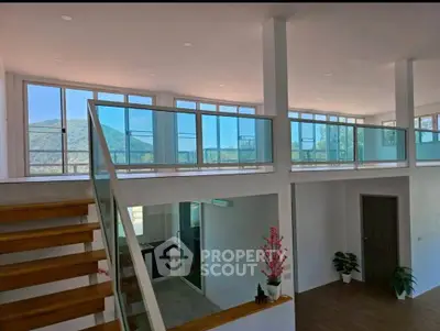Modern two-story interior with glass railings and scenic mountain view.