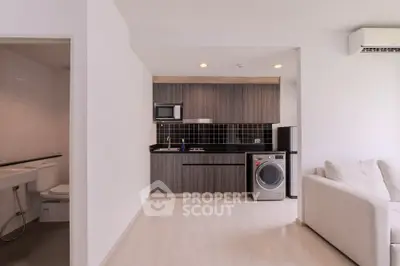 Modern studio apartment with compact kitchen and cozy living area, featuring a washing machine and air conditioning.