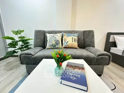 Modern living room with stylish gray sofa and decorative pillows, featuring a sleek coffee table and vibrant plant.