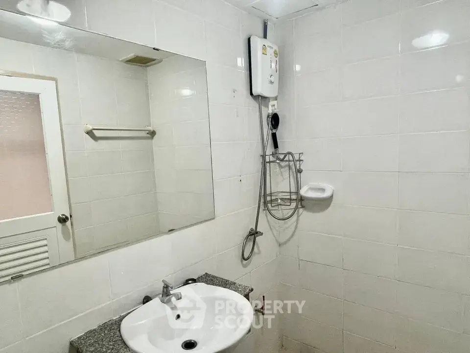 Compact bathroom with white tiles and modern sink in real estate property.