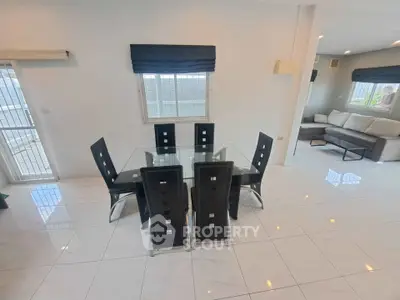 Modern dining area with glass table and stylish chairs in bright open-plan living space.
