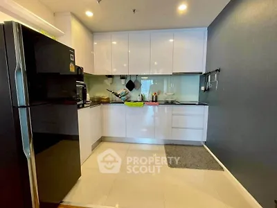 Modern kitchen with sleek white cabinets and black appliances in a stylish apartment.
