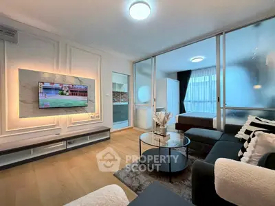 Modern living room with sleek furniture and ambient lighting, featuring a wall-mounted TV and stylish decor.
