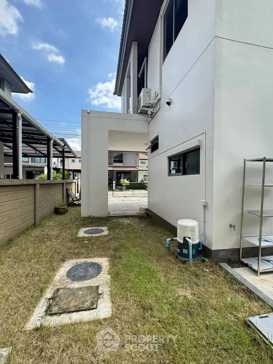 Modern residential building exterior with side yard and utility area.