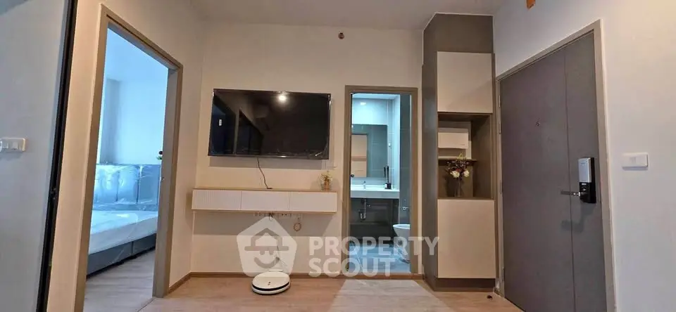 Modern apartment interior with wall-mounted TV and view into bedroom and bathroom