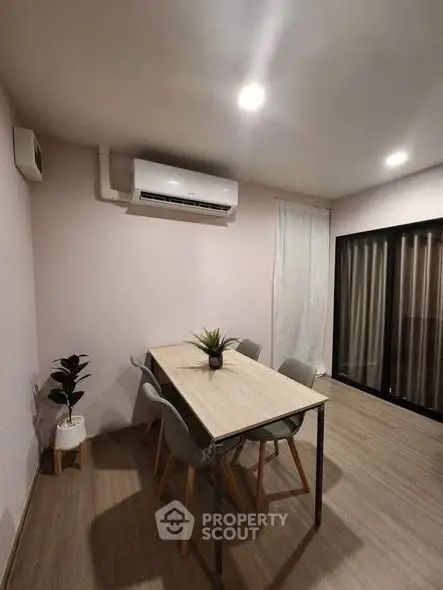 Modern dining area with sleek table, chairs, and air conditioning in a cozy apartment setting.