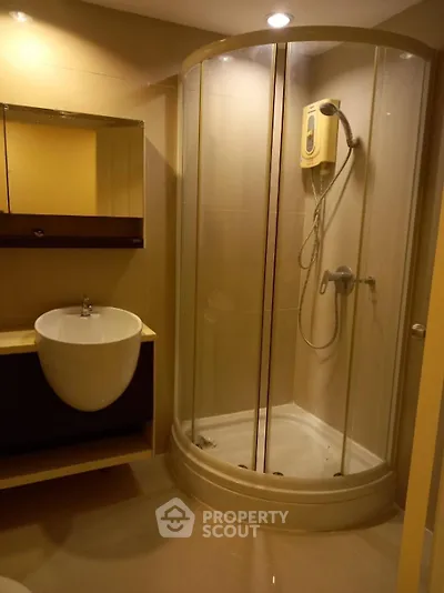 Modern bathroom with glass shower enclosure and sleek sink design.