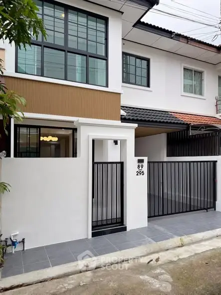 Modern townhouse exterior with sleek black gate and large windows