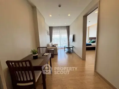 Modern apartment interior with cozy living room and dining area, featuring wooden flooring and natural light.