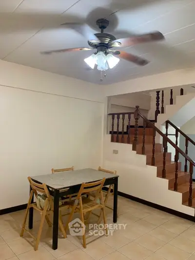 Cozy dining area with wooden staircase and ceiling fan in a modern home