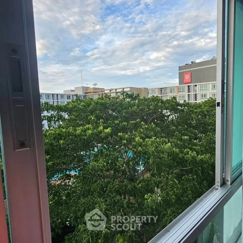 Stunning view from a high-rise window overlooking lush greenery and modern buildings.