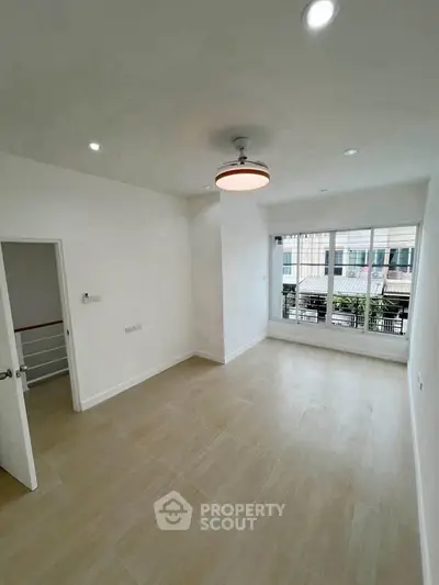 Spacious empty room with large window and modern ceiling light, perfect for customization.